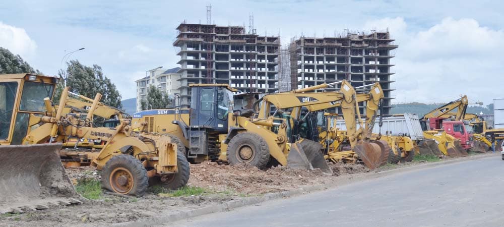 Contractor reviewing equipment financing documents next to heavy machinery