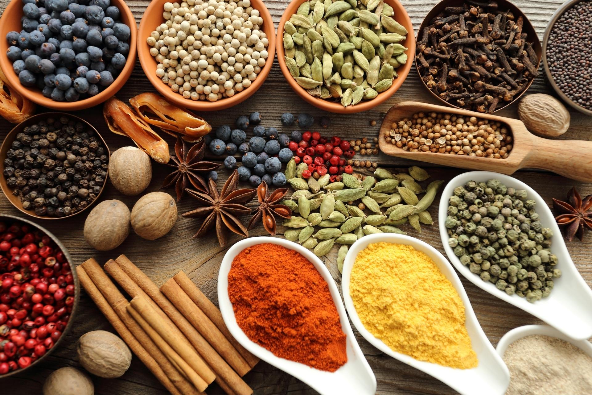Artisanal display of authentic Ethiopian culinary spices, whole pods, korarima, berbere chili, cardamom, and turmeric in bowls and spoons